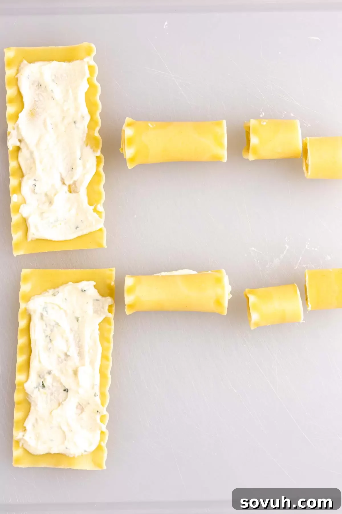Freshly cooked lasagna noodles laid flat on a cutting board, with a small bowl of ricotta filling ready for assembly.