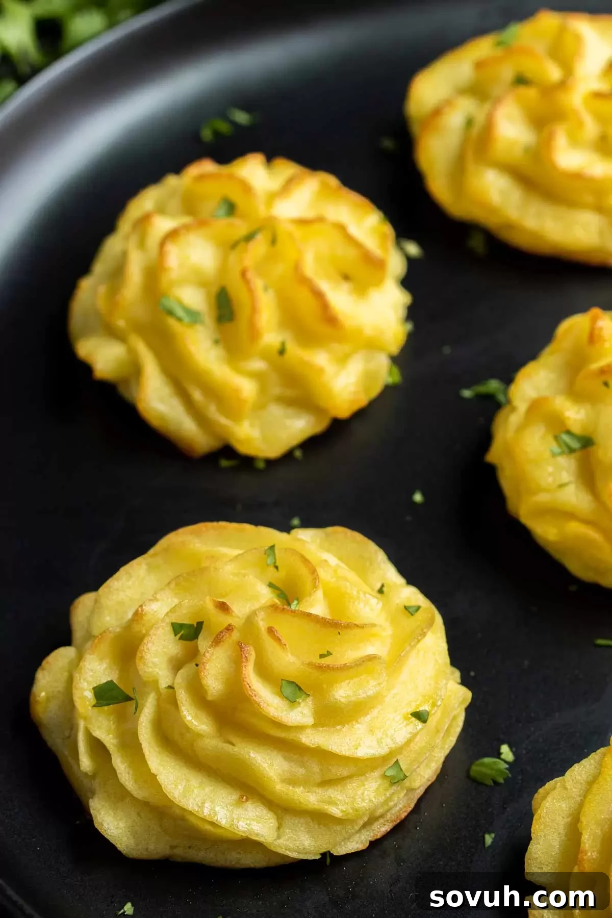 Duchess Potatoes arranged elegantly on a platter and garnished with fresh parsley.
