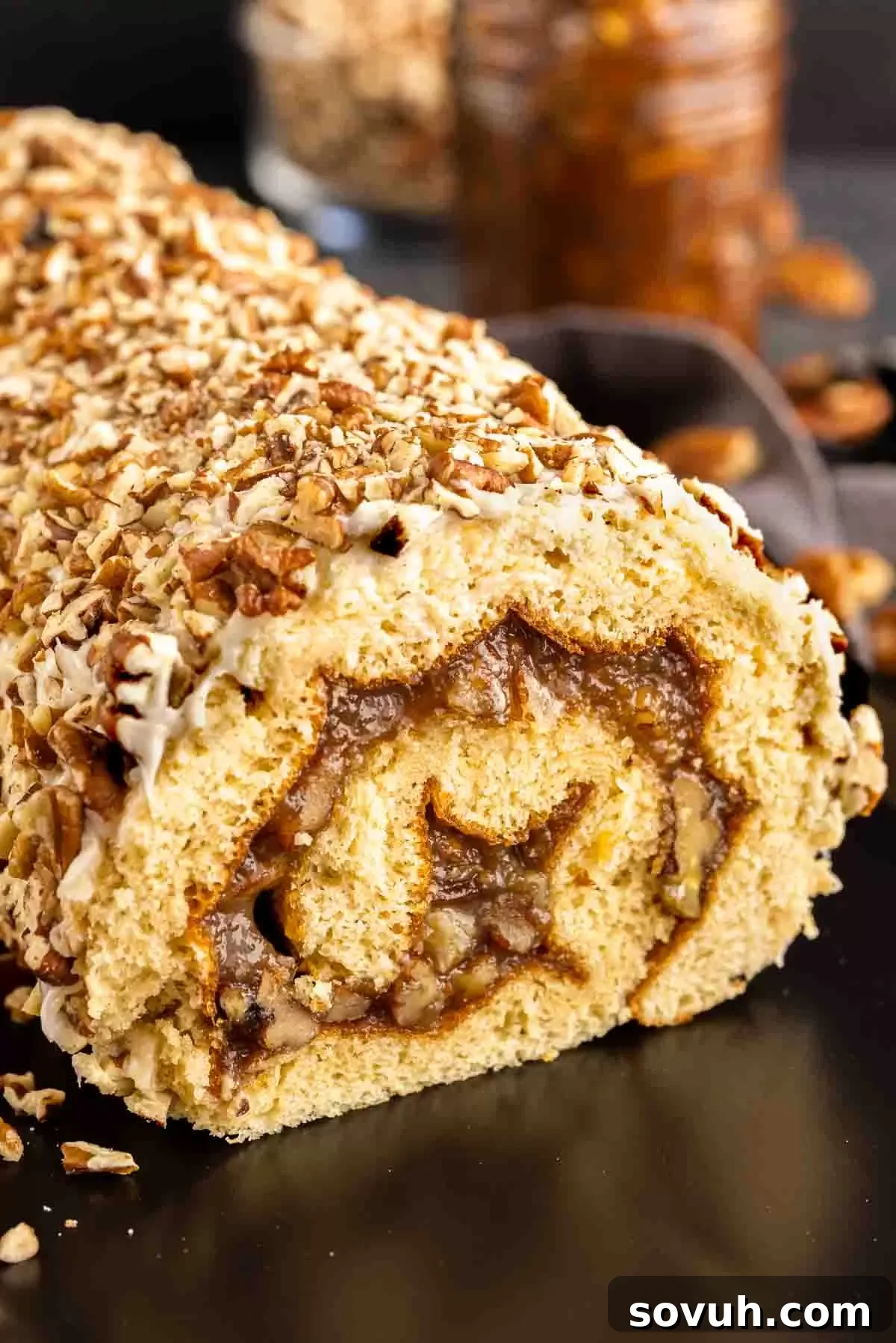 Pecan Pie Cake Roll on a black platter coated in chopped pecans