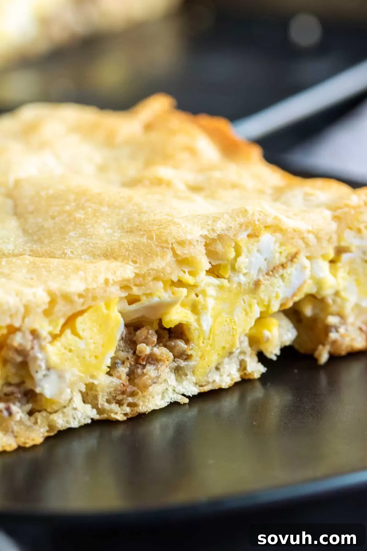 A close-up view of the interior layers of a slice of Eggs and Sausage Crescent Roll Breakfast Casserole.