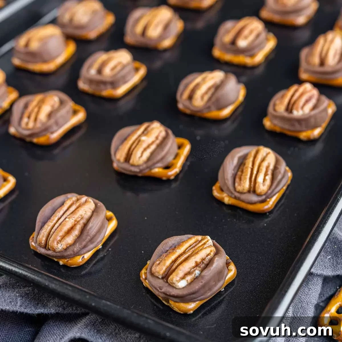 Rolo Pretzel Turtle Candy cooling on a parchment-lined sheet pan