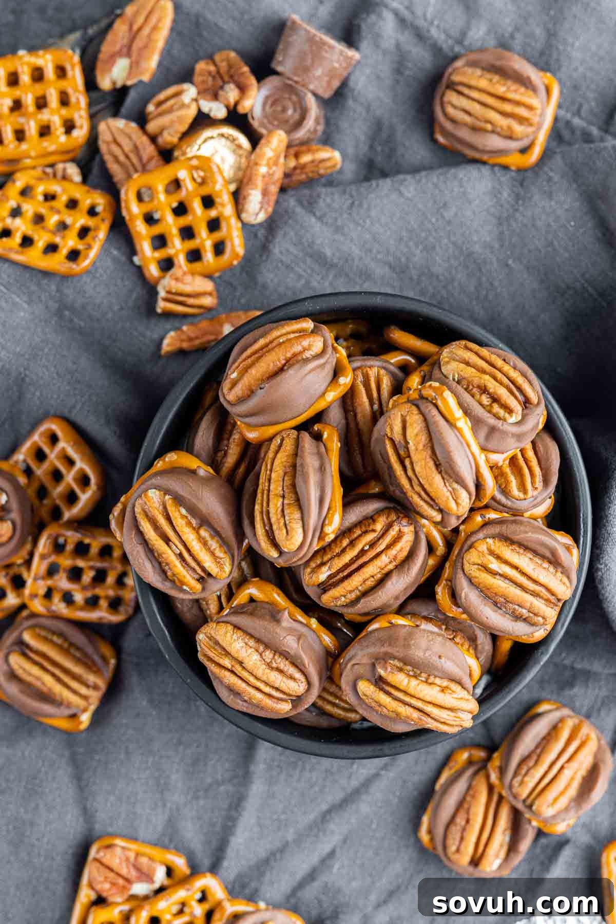 Close-up of Rolo Pretzel Turtle Candies in a black bowl and scattered on a gray cloth background