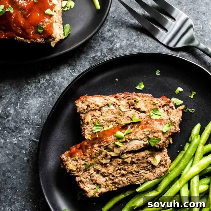 Keto Meatloaf with Pork Rinds on a white plate with green beans and a fork, ready to be enjoyed.