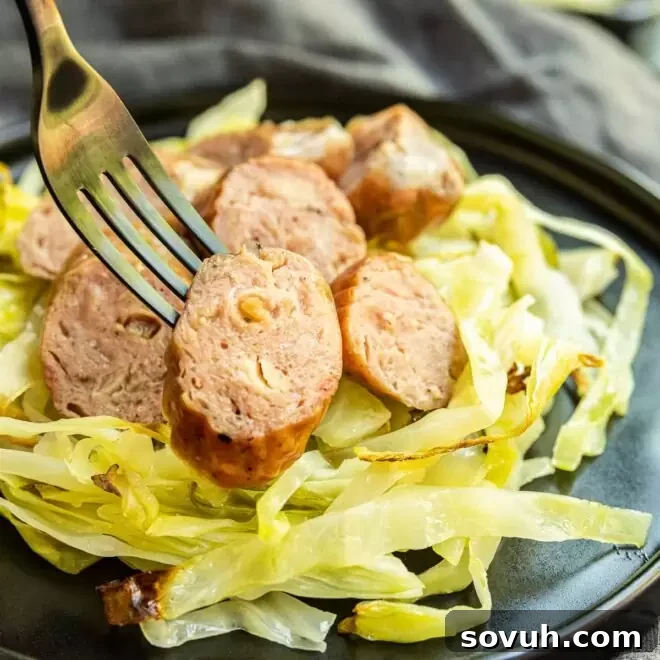 Sheet Pan Sausage and Cabbage on a plate, with a piece of sausage on a fork, ready to eat.