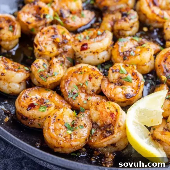 Gambas Pil Pil (Chili Garlic Shrimp) sizzling in a chili garlic oil with fresh lemon slices, served in a rustic earthenware dish.