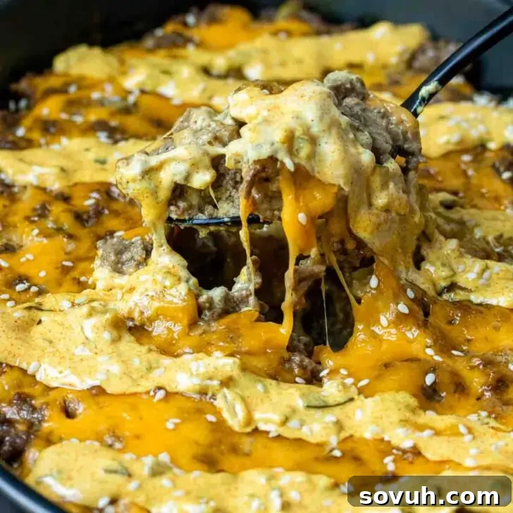 A spoon lifting a portion of Keto Big Mac Casserole from a baking dish.