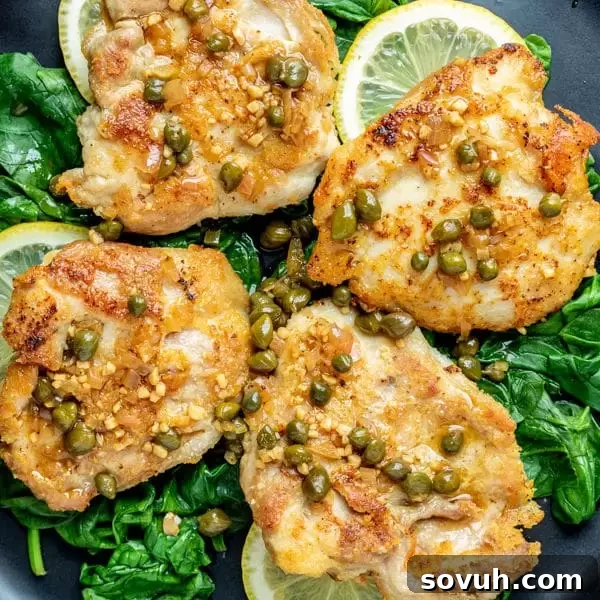 Delicious Keto Chicken Piccata with golden Parmesan-crusted chicken thighs and a vibrant lemon caper sauce, garnished with fresh parsley.