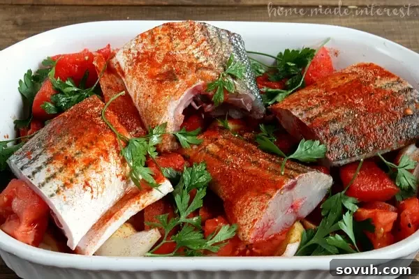 Raw rockfish steaks nestled amidst chopped red and white potatoes, plum tomatoes, sliced onions, and minced garlic in a baking dish, before baking in the Portuguese style. Seasoned with olive oil, paprika, salt, pepper, and fresh parsley, this healthy recipe is ready for the oven.