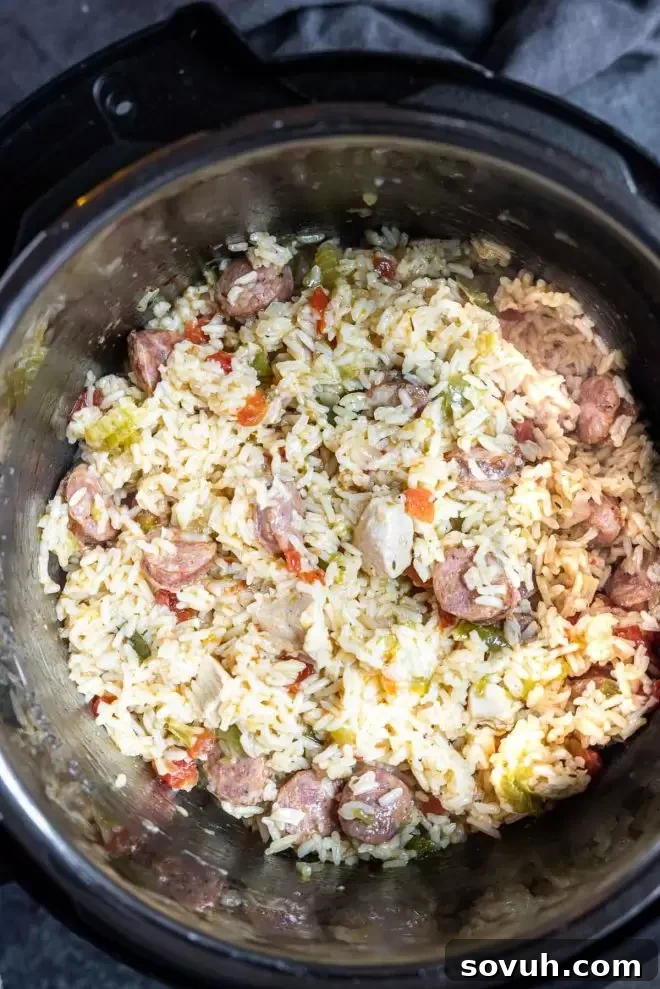 Instant Pot Jambalaya cooking and simmering inside the Instant Pot inner pot, showing a mix of rice, chicken, and sausage.