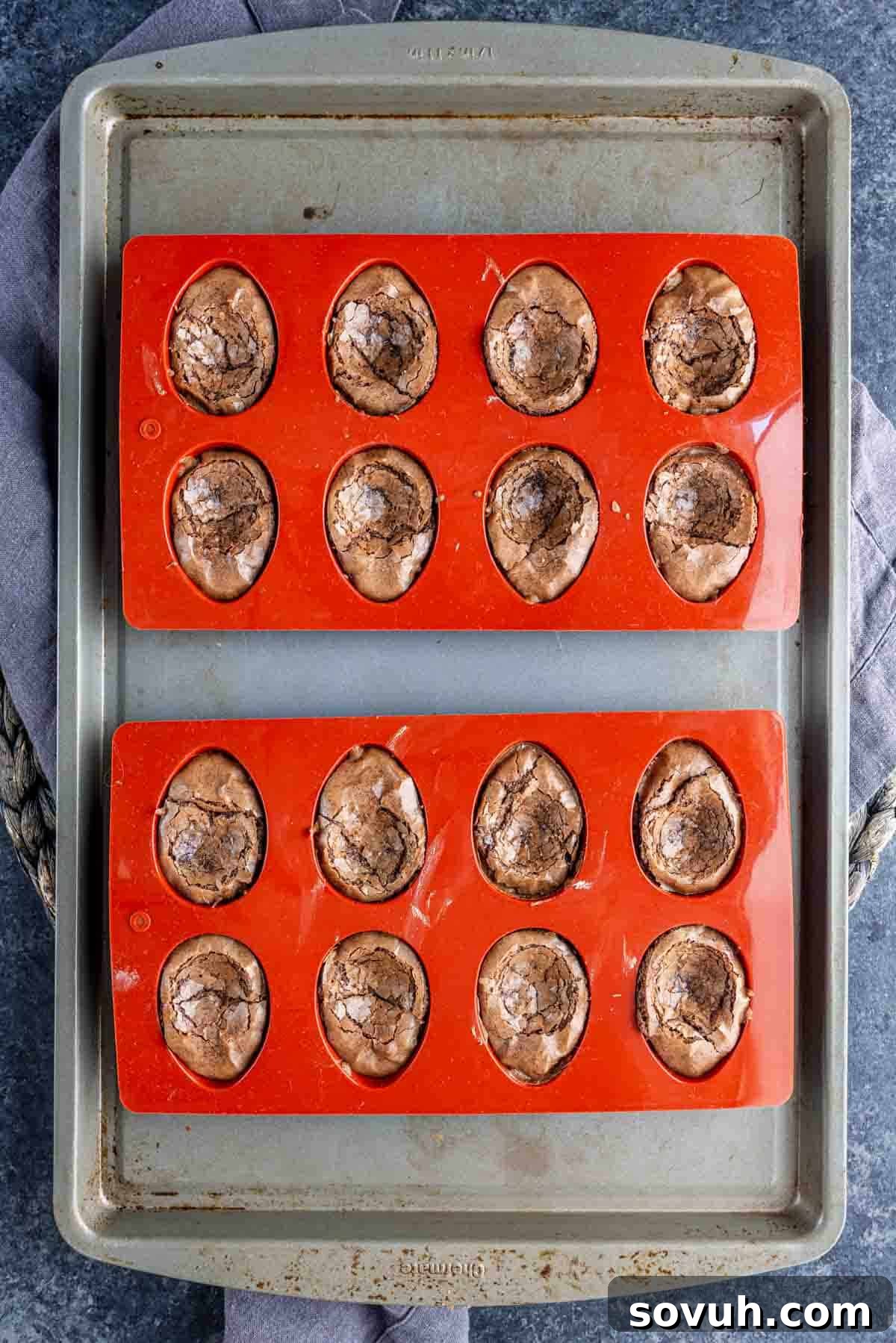 Devilish Easter Brownies from a Box 5 Two silicone baking molds filled with twelve chocolate, egg-shaped Deviled Brownies sit on a metal baking sheet—an easy Easter dessert perfect for spring parties.
