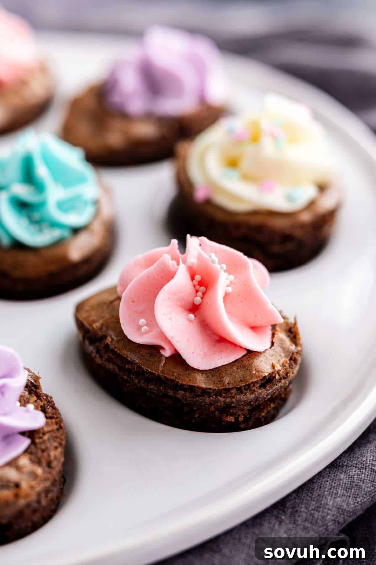 Devilish Easter Brownies from a Box 8 Close-up of heart-shaped Easter brownies topped with colorful swirls of frosting and sprinkles on a white plate—an easy Easter dessert that's as festive as it is delicious.