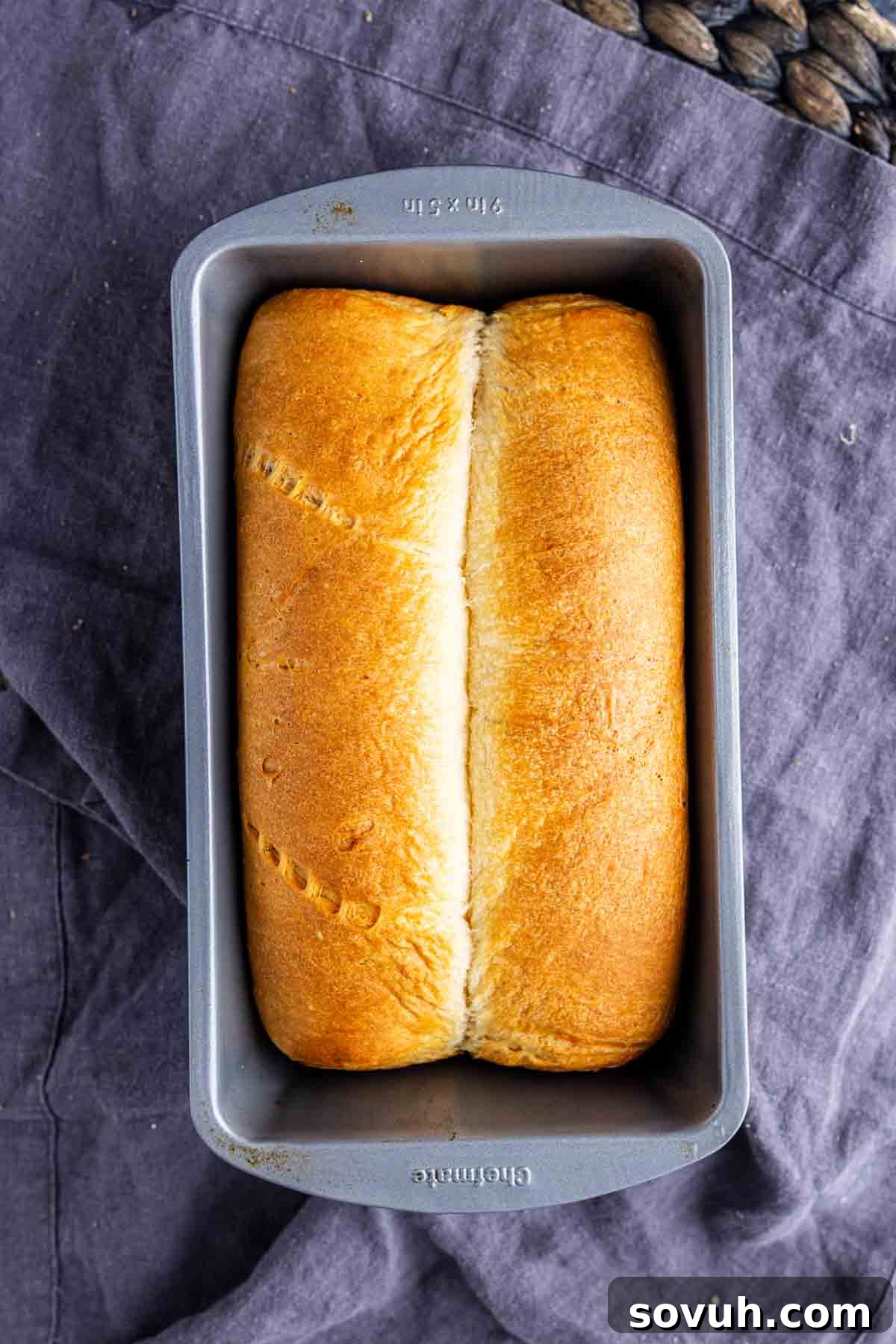 The Viral Golden Crescent Bake 5 A loaf of golden-brown crescent roll bread in a rectangular metal baking pan, resting on a dark cloth, freshly baked and ready to be enjoyed.