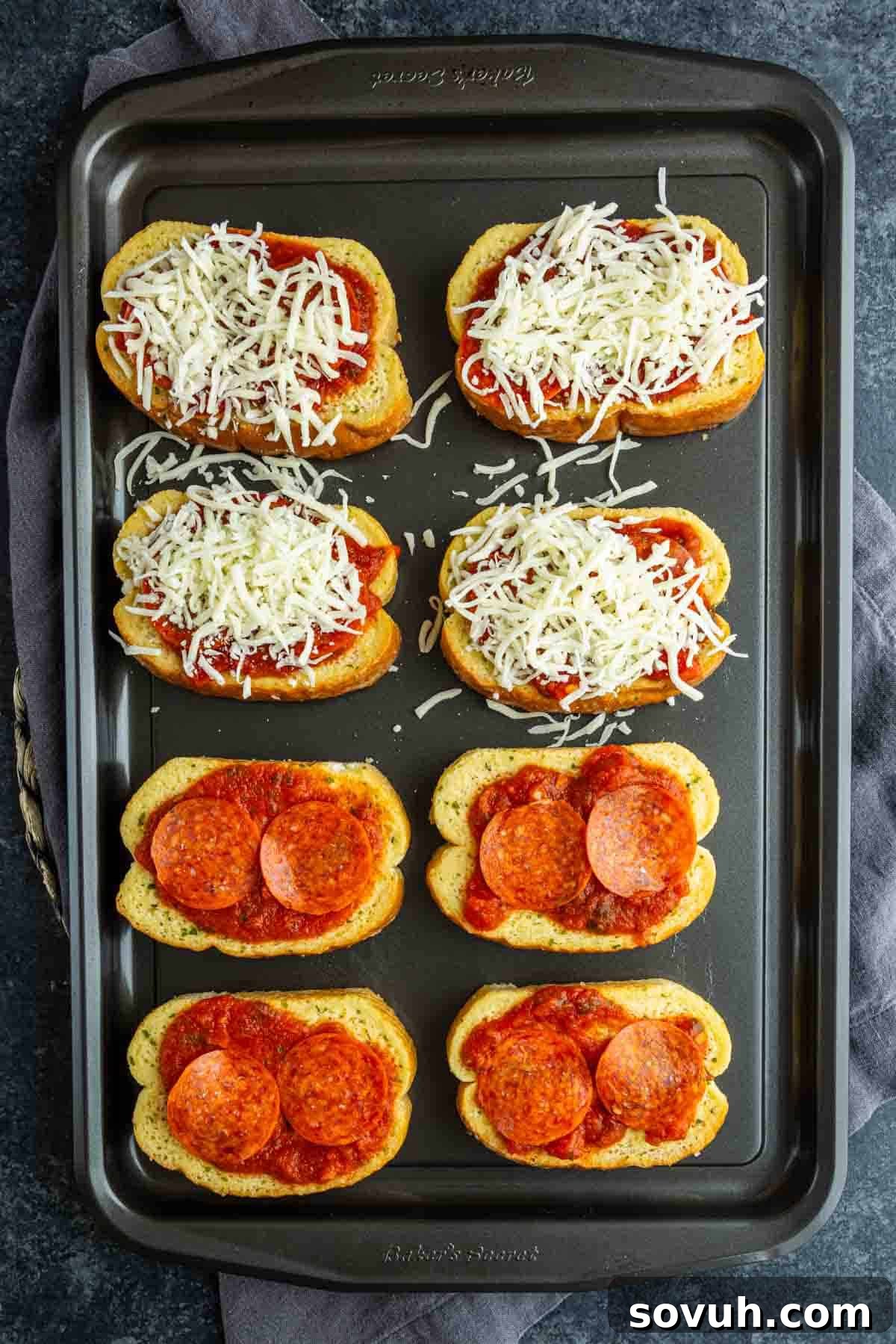 15-Minute Texas Toast Pizza Recipe for Quick Family Dinner 4 A baking tray with eight pieces of bread; four are Garlic Bread Pizza topped with sauce, cheese, and pepperoni, while four have just sauce and cheese—ready to be baked as easy pizza toast recipe French bread pizzas.