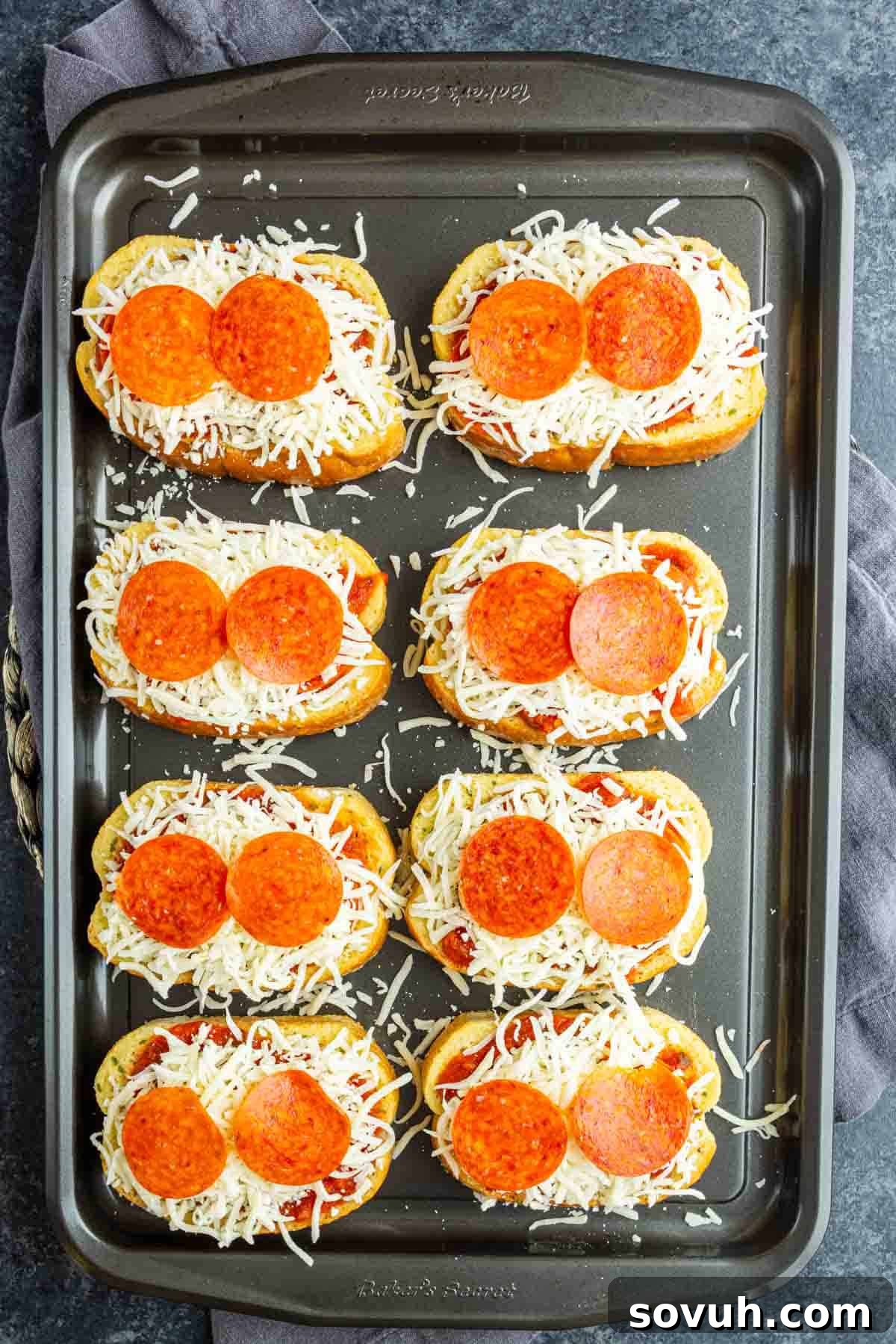 15-Minute Texas Toast Pizza Recipe for Quick Family Dinner 5 Eight slices of Texas Toast Pizza are topped with shredded cheese and pepperoni, arranged on a baking sheet—an easy pizza toast recipe ready to be baked.