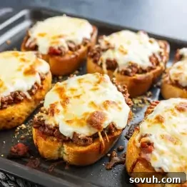 Texas Toast Garlic Bread Lasagna Recipe: Cheesy Weeknight Dinner 7 Six slices of Texas Toast Lasagna on a baking tray, each topped with seasoned ground beef, tomato sauce, and melted mozzarella cheese for a delicious twist on classic garlic bread.