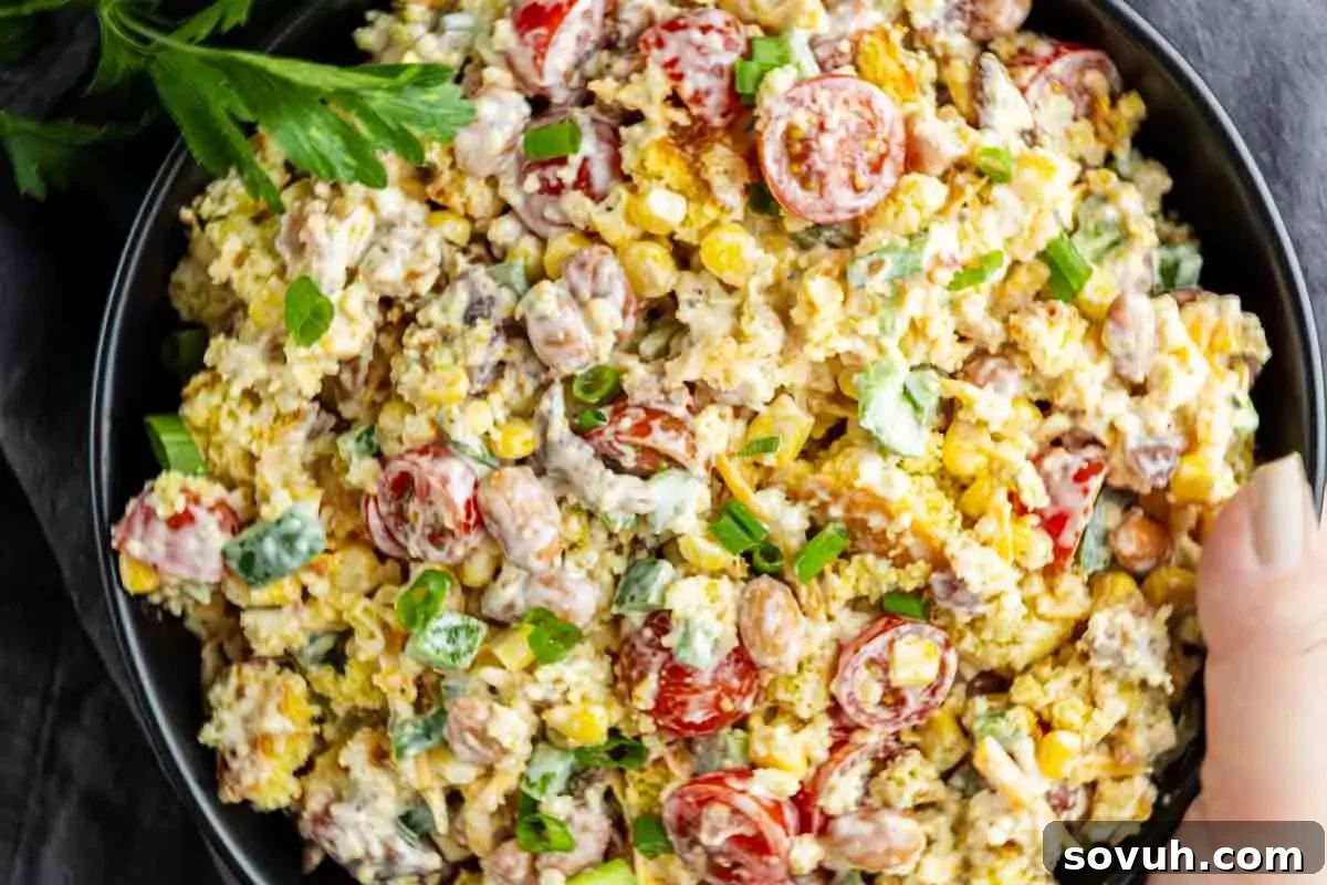 Southern Cornbread Salad Recipe for Potlucks and BBQs 2 A bowl of salad with corn, cherry tomatoes, beans, green onions, and a creamy dressing, garnished with fresh herbs—perfect as a summer BBQ side or classic Southern potluck side dish.