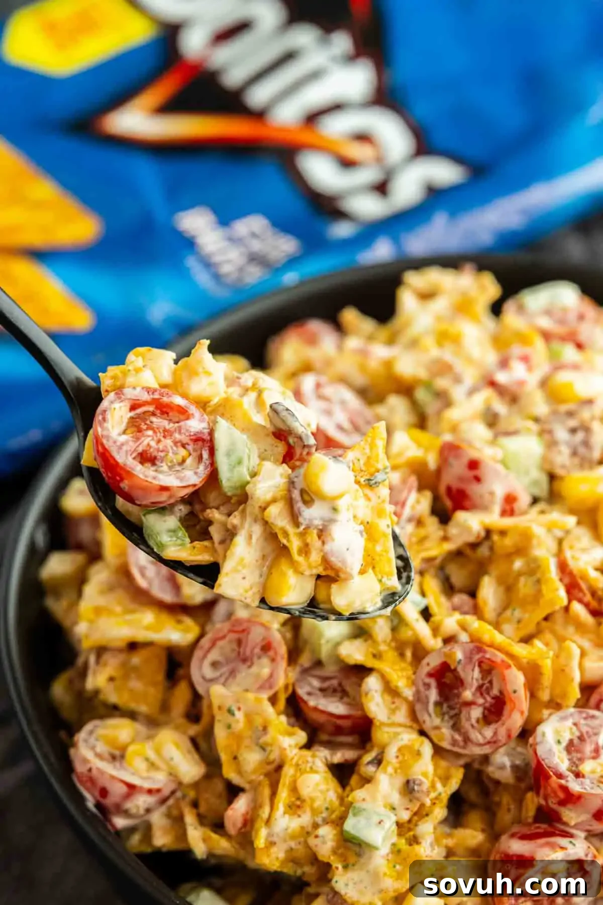 Crunchy Cool Ranch Doritos Salad with Bacon & Sweet Corn 6 A spoonful of Cool Ranch Doritos Salad with cherry tomatoes, corn, cucumber, and creamy dressing, with a bag of Doritos in the background.