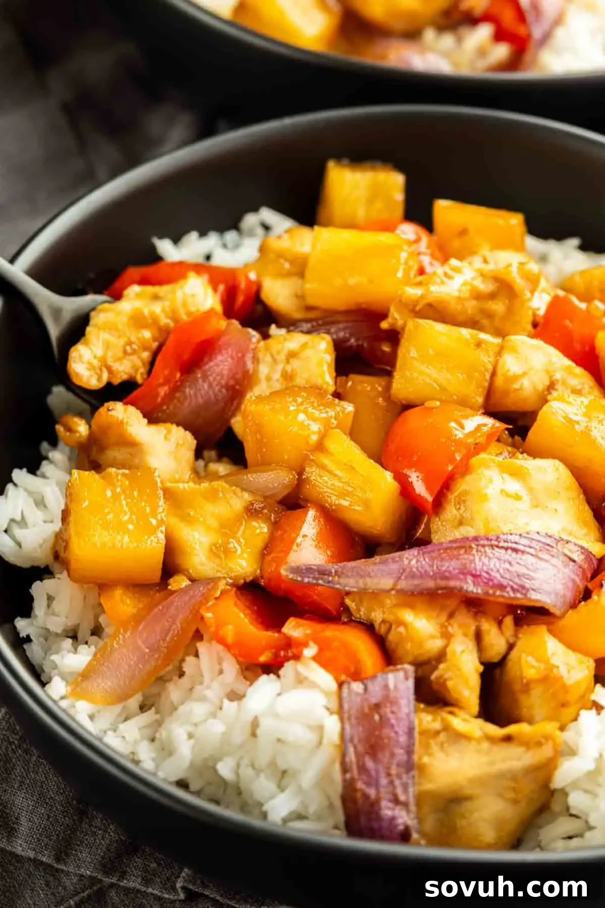 Sheet Pan Hawaiian Chicken with Pineapple and Teriyaki Glaze 6 A bowl of white rice topped with stir-fried chicken, pineapple chunks, red bell peppers, carrots, and red onions—perfect for an easy weeknight dinner.