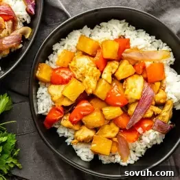 Sheet Pan Hawaiian Chicken with Pineapple and Teriyaki Glaze 7 A bowl of white rice topped with chunks of chicken, pineapple, red bell pepper, and red onion in a brown sauce—this easy weeknight dinner is a flavorful one pan Hawaiian chicken recipe the whole family will love.