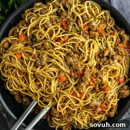 Viral Cajun Dirty Spaghetti Recipe for Dinner That Delights 6 A pan filled with cooked noodles, ground meat, and diced red bell peppers captures the essence of viral Dirty Spaghetti, with metal tongs resting inside.