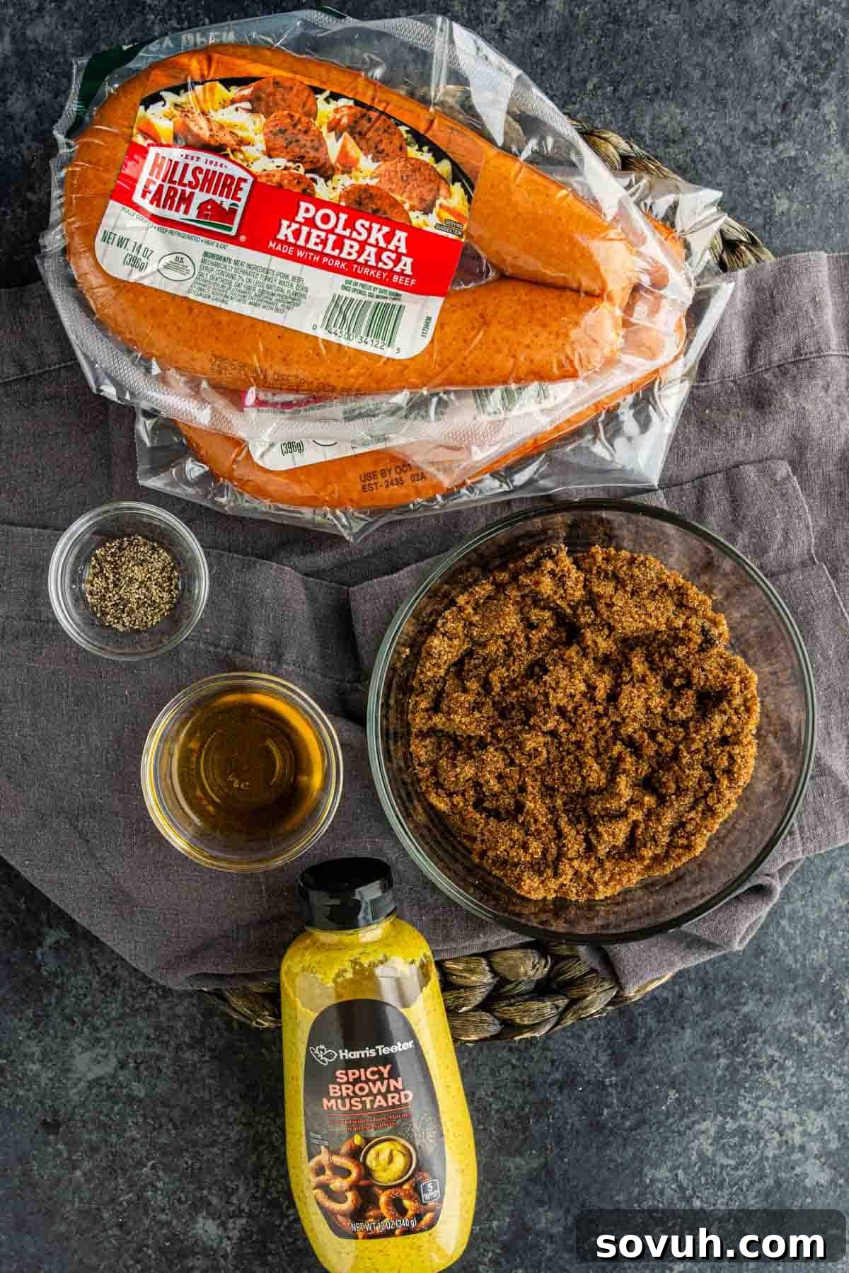 Oven-Baked Brown Sugar Barbecue Kielbasa Recipe 4 A package of Polska kielbasa, brown sugar, spicy brown mustard, black pepper, and honey on a gray cloth—perfect ingredients for a flavorful BBQ kielbasa bites or your next favorite kielbasa appetizer recipe.