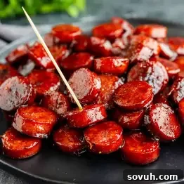 Oven-Baked Brown Sugar Barbecue Kielbasa Recipe 8 A black plate filled with glazed, sliced BBQ kielbasa bites, with a toothpick inserted into one of the slices for an irresistible kielbasa appetizer recipe.